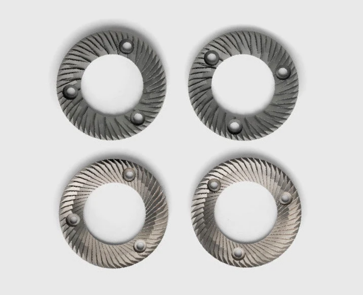 Four circular metallic ring-shaped  burr grinders arranged in a grid on a light gray background. Each ring has a textured spiral pattern and three small raised circular details near the edge.