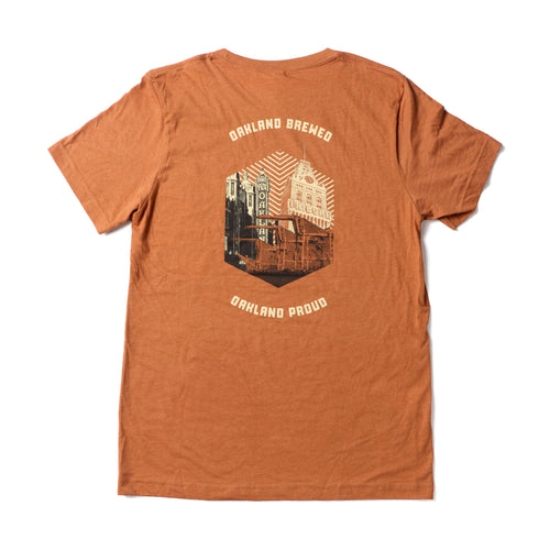 Orange t-shirt with 'Oakland Brewed' and 'Oakland Proud' text and graphic on a white background