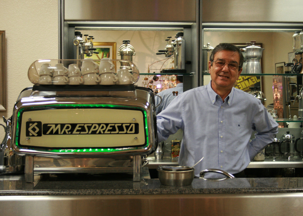 Carlo Di Ruocco behind the counter at the caffe with a vintage Mr. Espresso machine