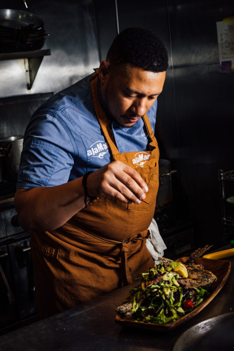 Chef at Sobre Mesa and AlaMar preparing a whole fish dish
